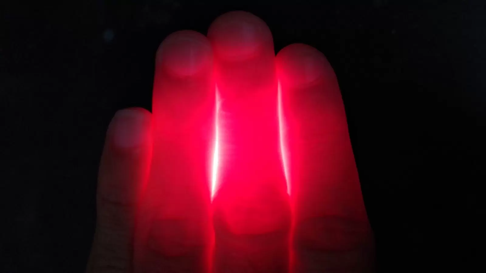 A person's hand with a red light on it.