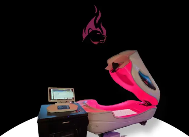 "High-tech wellness pod with a partially open lid, glowing with pink interior lighting. A control station with a tablet interface is positioned beside the pod. A stylized flame and panther logo is visible in the background."